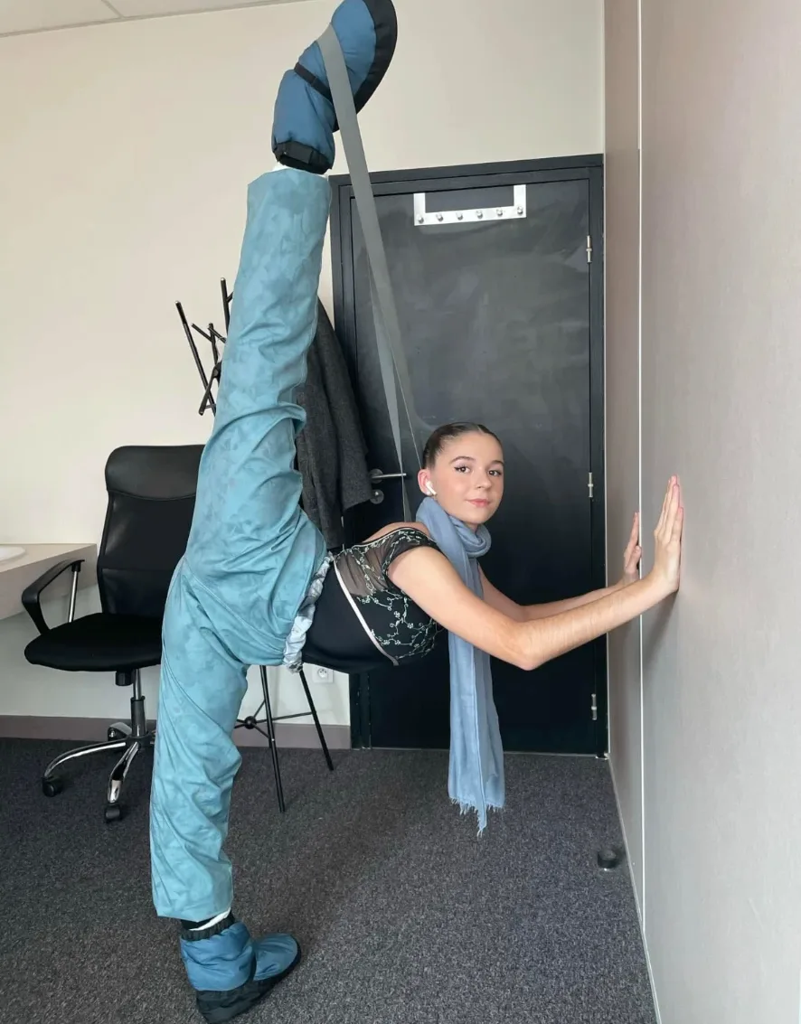 Jeune danseuse en grand écart vertical contre un mur pendant l'échauffement