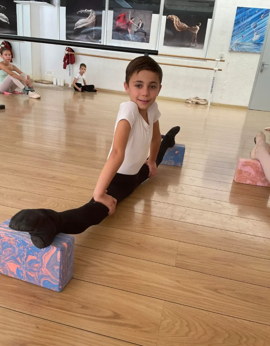 Jeune danseur en grand écart facial sur briques lors d'un cours de barre à terre