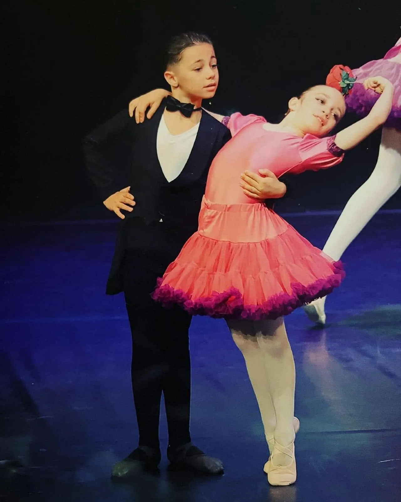 Duo d'élèves en spectacle sur scène, danseuse en tutu rose et danseur en costume