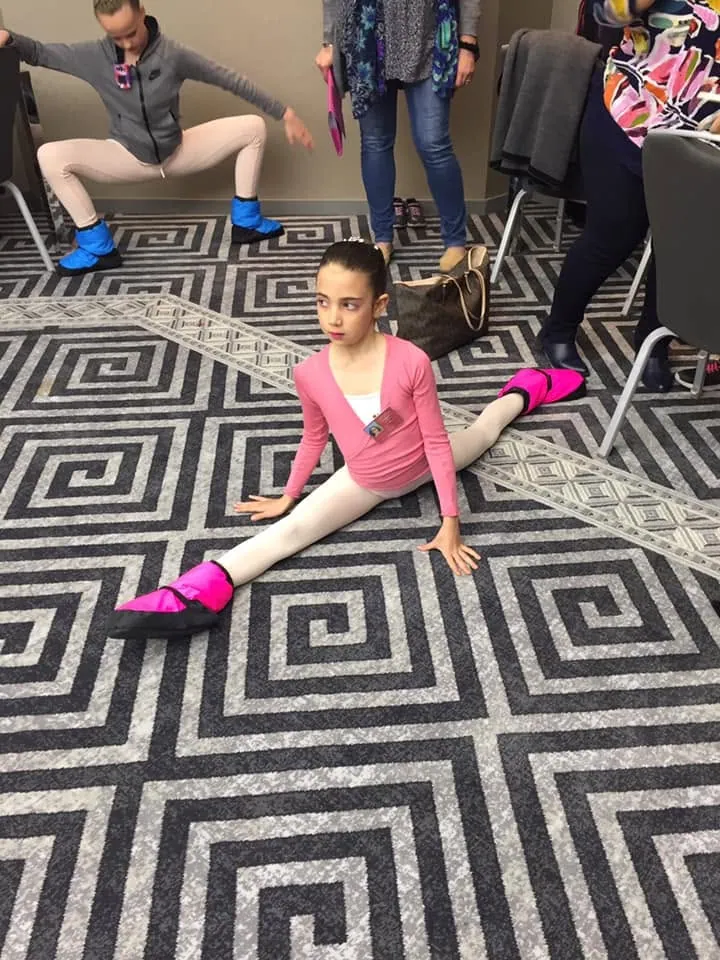 Jeune élève en grand écart pendant l'échauffement avant son passage en concours