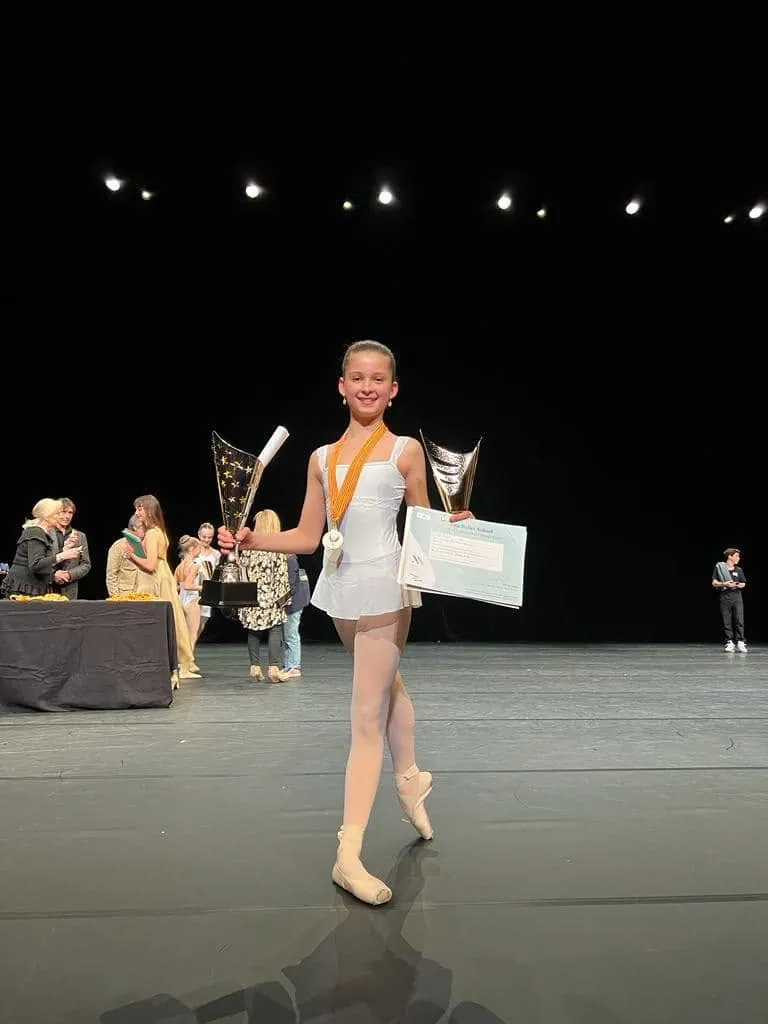 Élève lauréate sur scène avec deux trophées, médaille et diplôme
