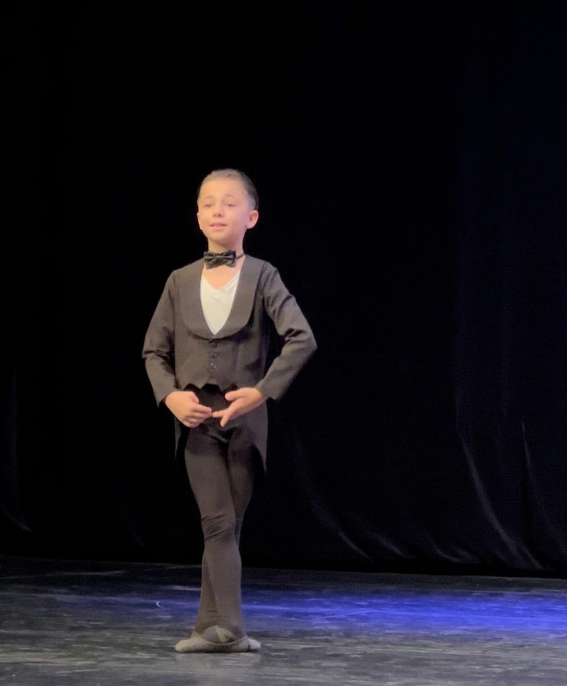 Jeune danseur en costume et nœud papillon sur scène