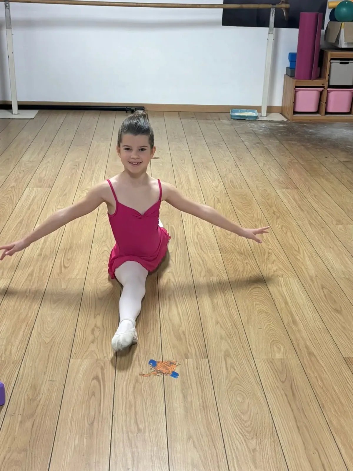 Jeune élève en tenue rose réalisant une position au sol dans le studio