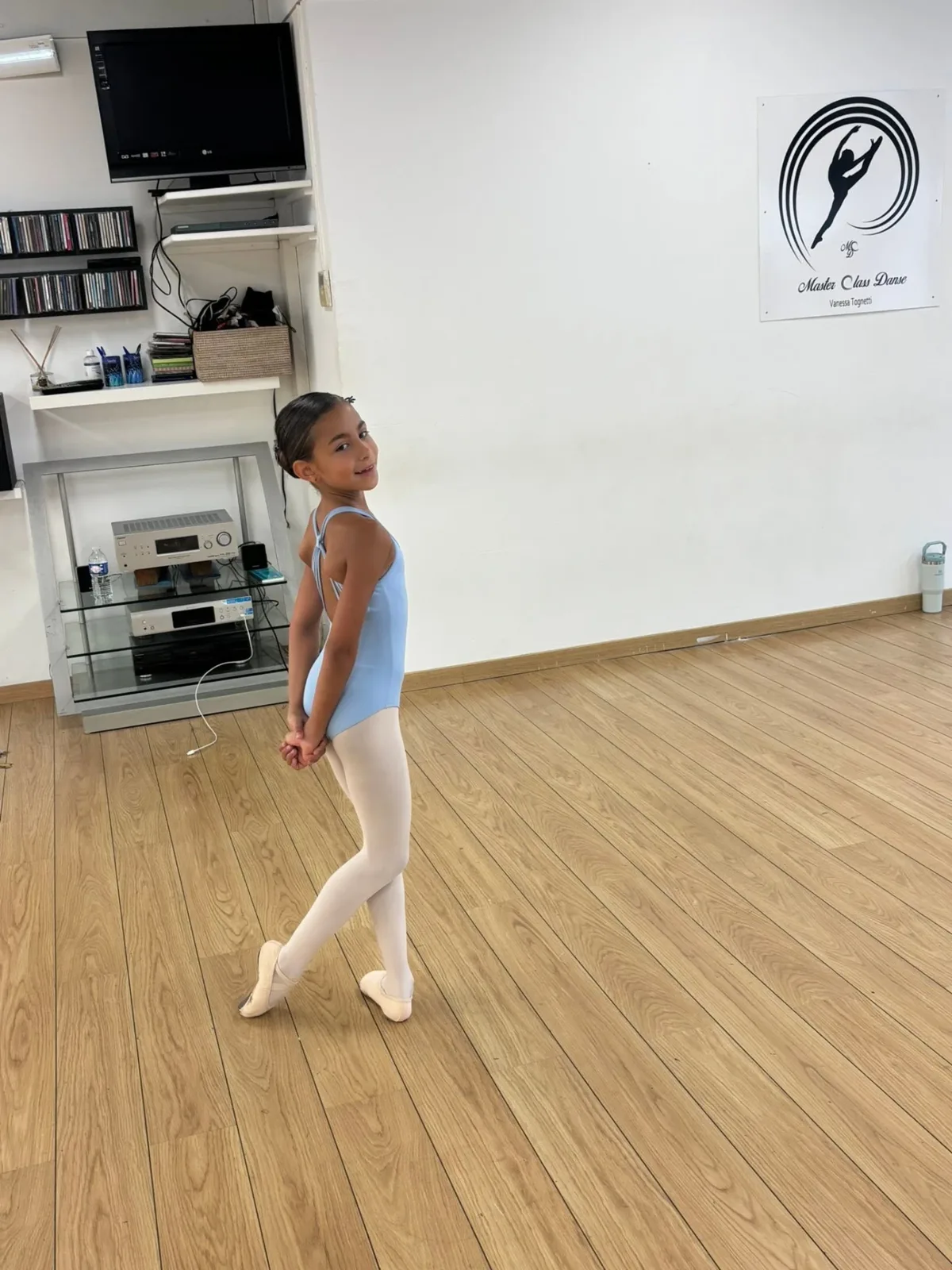 Jeune danseuse en tenue bleu clair prenant une pose classique dans le studio