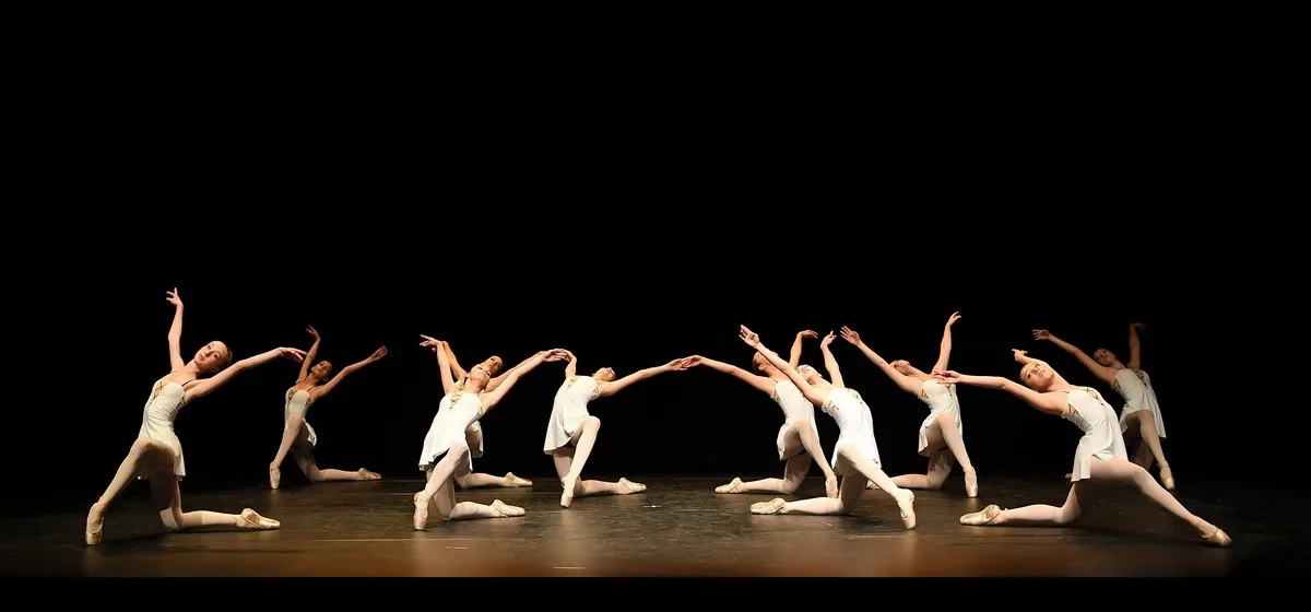 Ensemble de danseuses classiques en tuniques blanches alignées sur scène