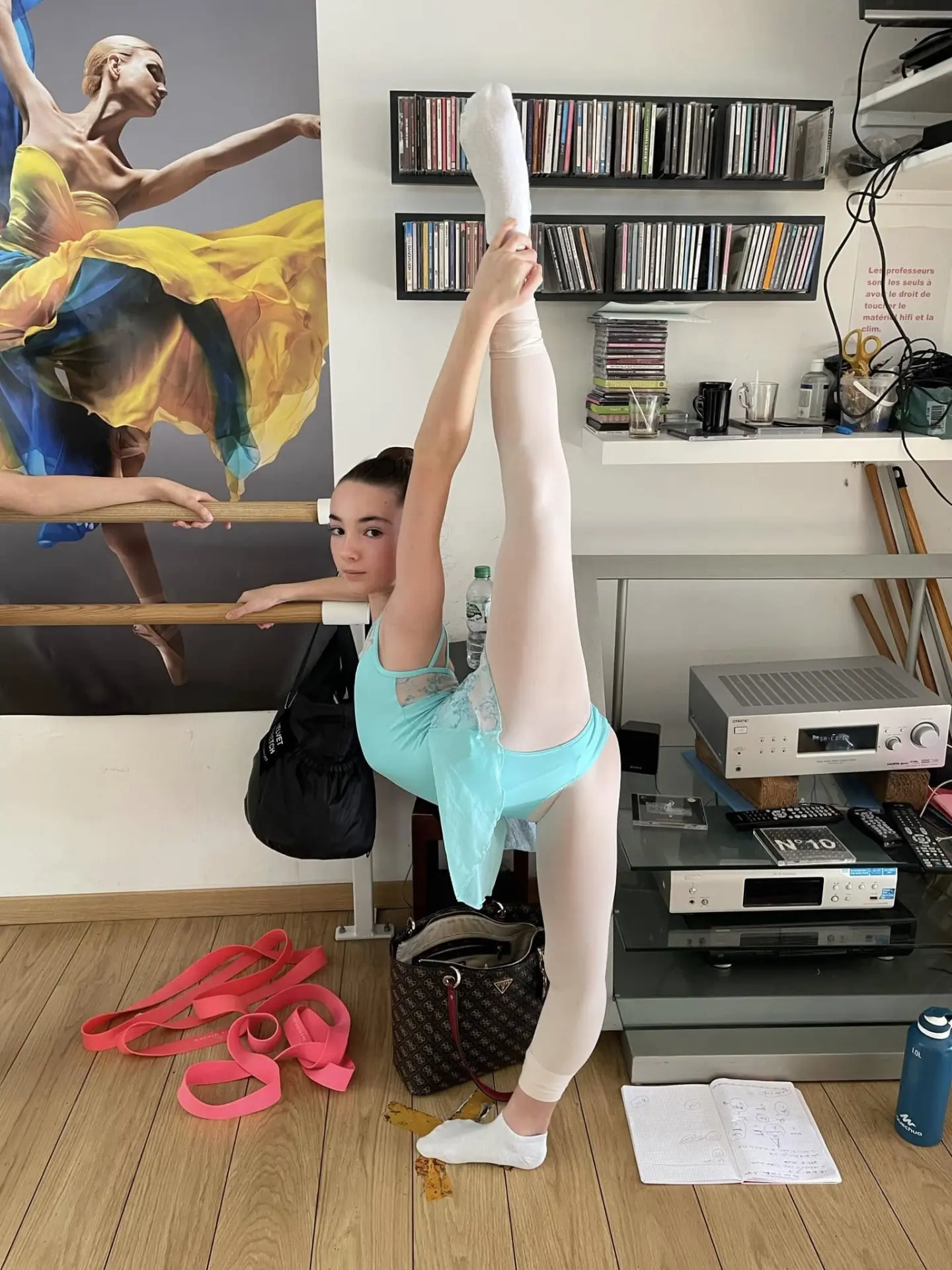 Élève en grand écart vertical à la barre pendant l'échauffement en studio