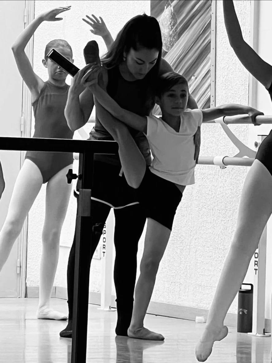 Professeure corrigeant un jeune danseur à la barre