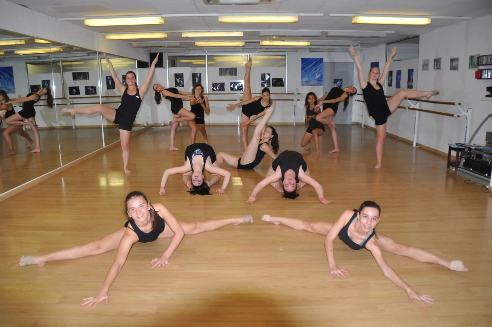 Groupe de danseuses en tenues noires en poses contemporaines dans le studio