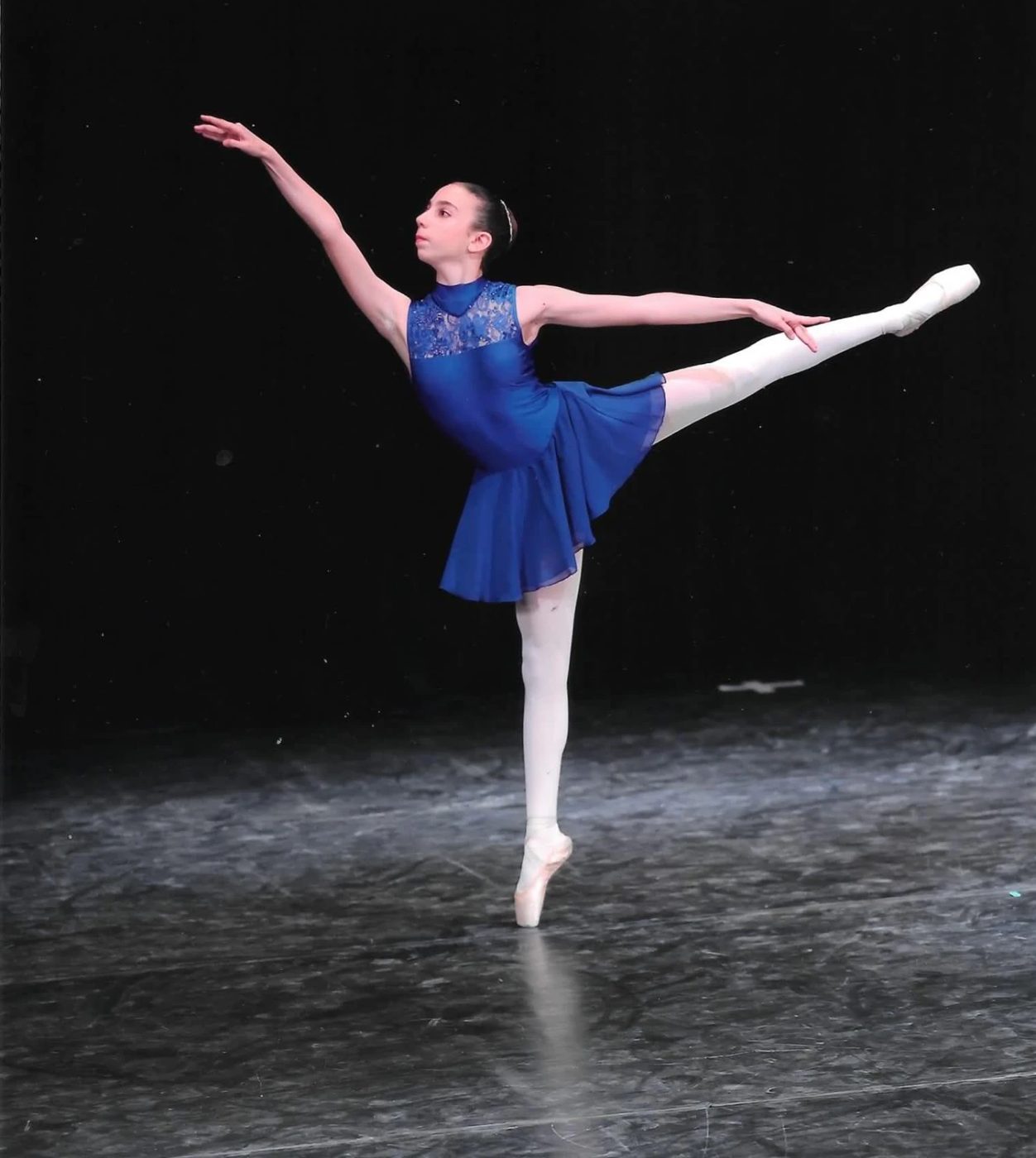 Danseuse en tunique bleue en arabesque sur pointes au Concours International Master Danza
