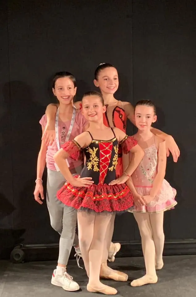 Quatre élèves en costumes de scène posant en coulisses