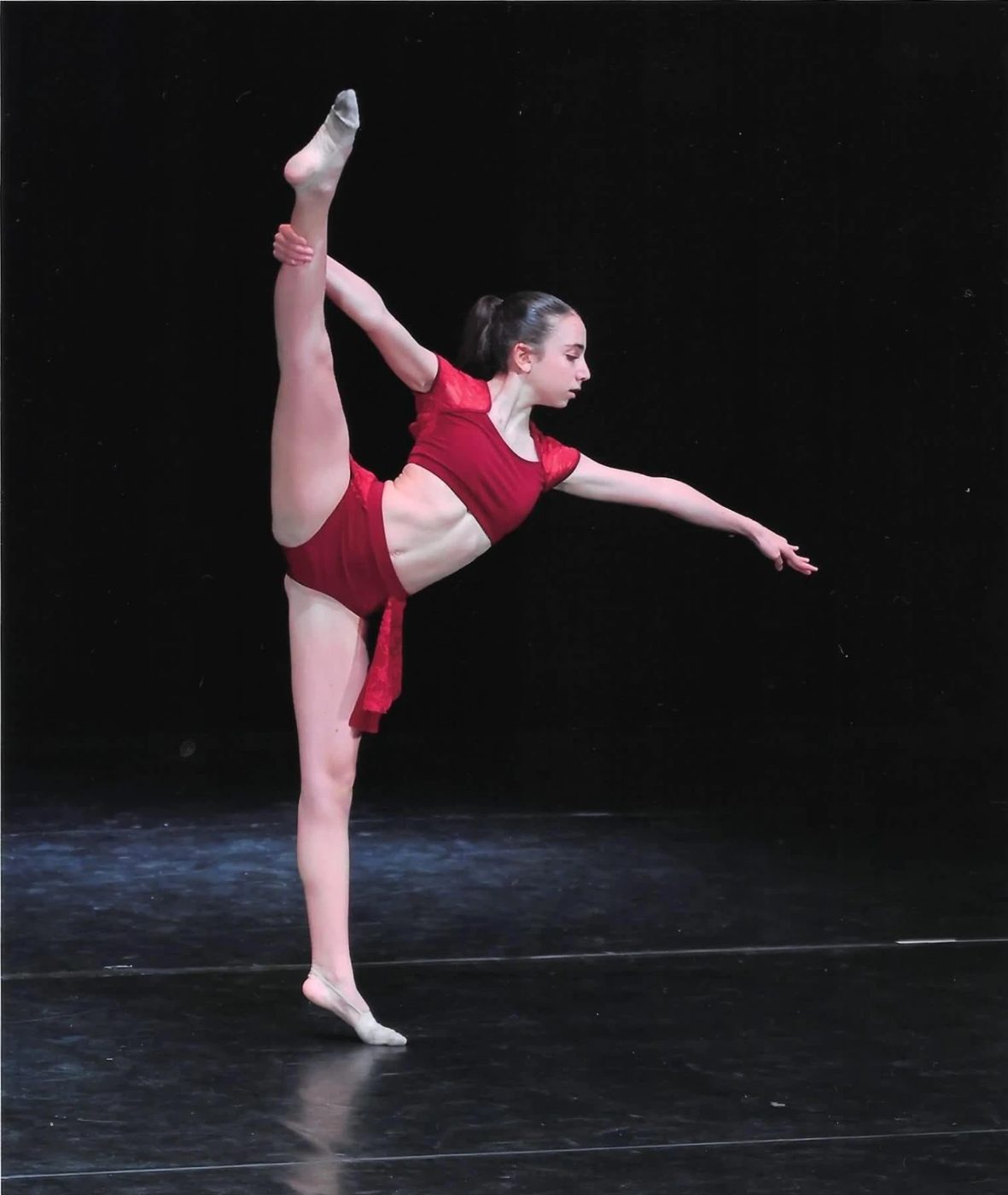 Danseuse en costume rouge en grand écart vertical au Concours International Master Danza