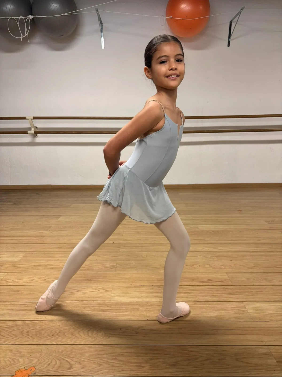Jeune danseuse en tenue bleu clair travaillant une pose classique dans le studio
