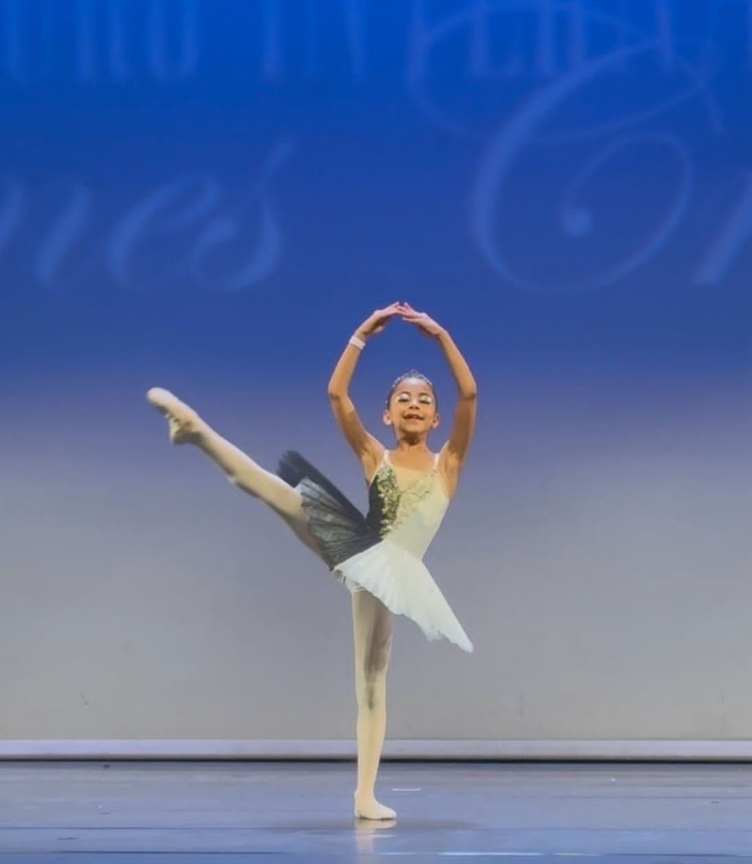 Jeune danseuse en tutu blanc et vert en attitude sur pointes en concours