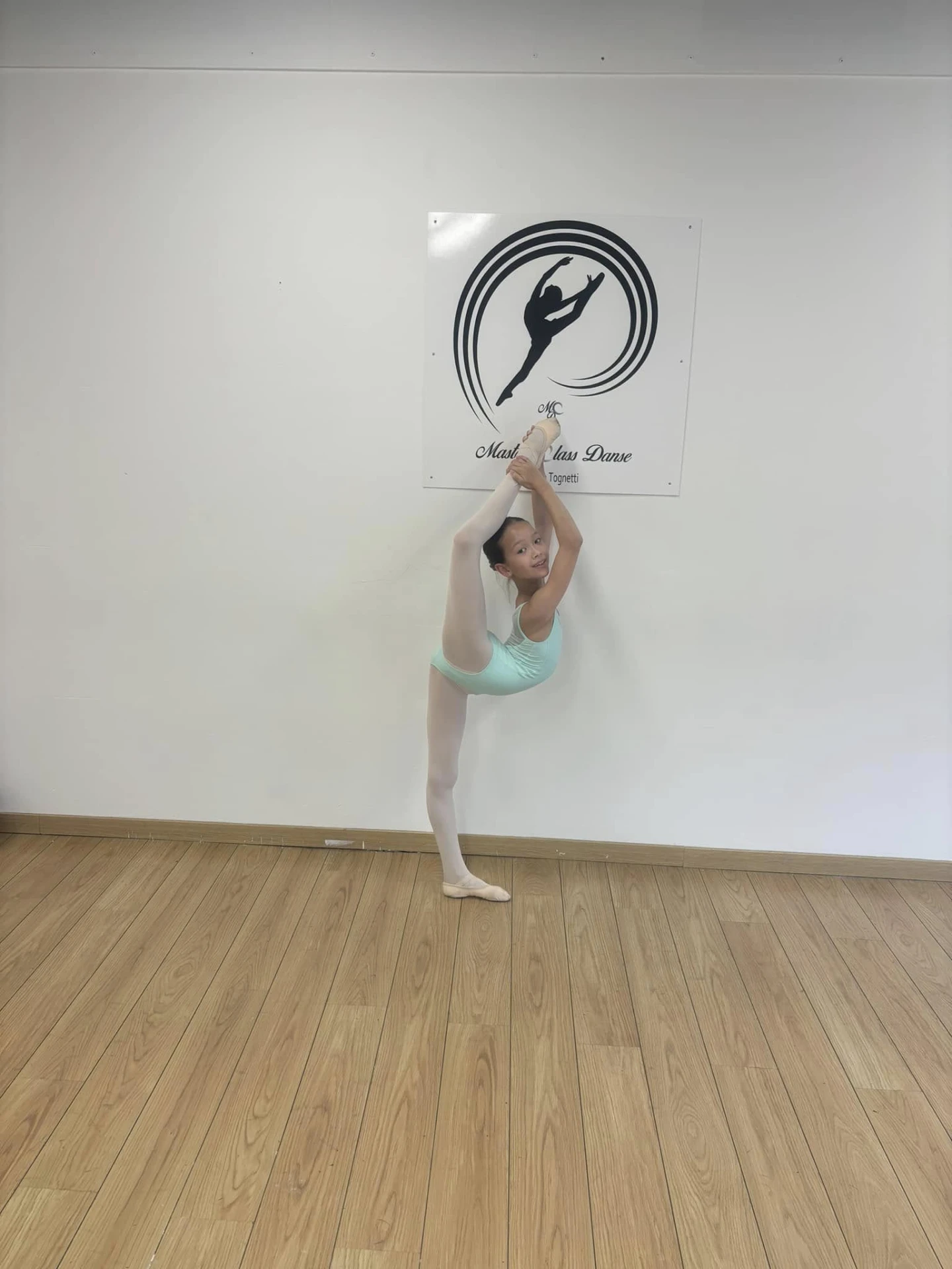 Jeune danseuse en développé devant le logo Master Class Danse en studio