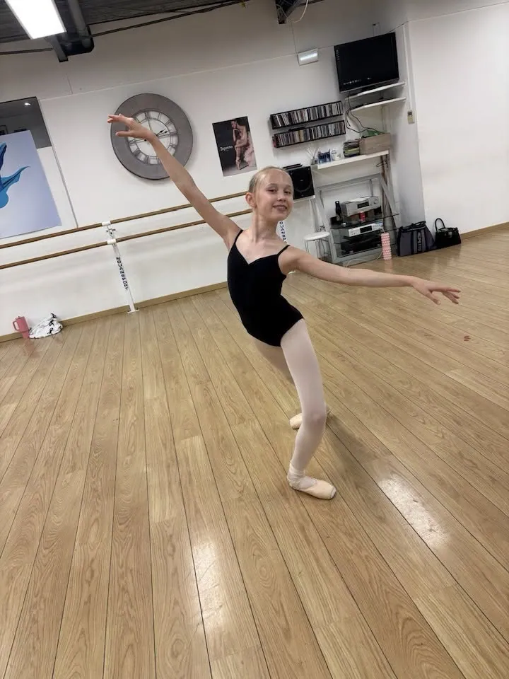 Jeune danseuse classique en justaucorps noir en pose au studio