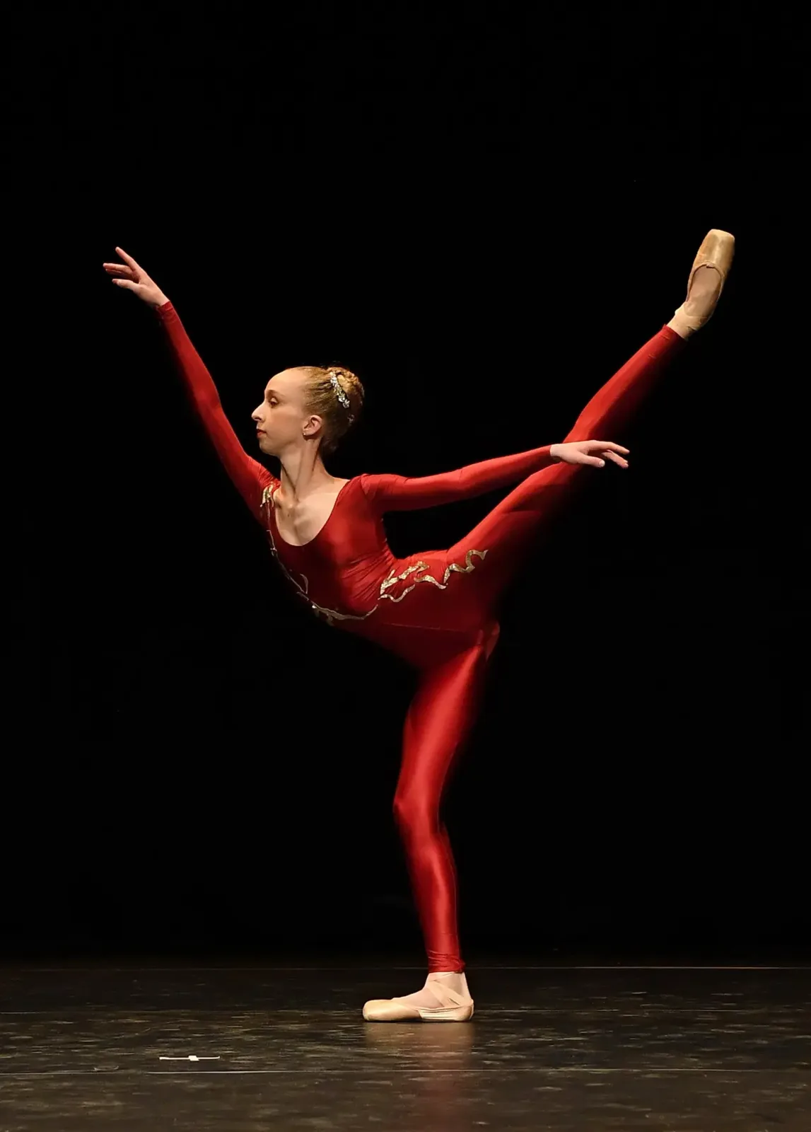 Danseuse classique en arabesque sur pointes, costume rouge et or, sur scène