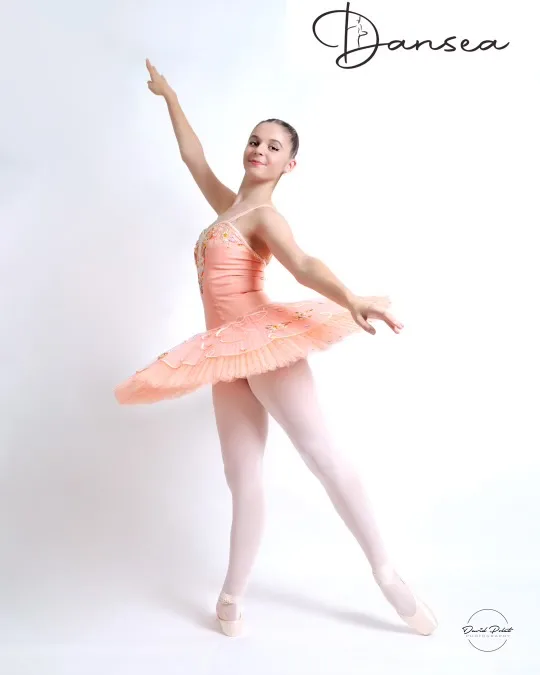 Jeune danseuse classique en tutu pêche posant sur pointes en studio photo