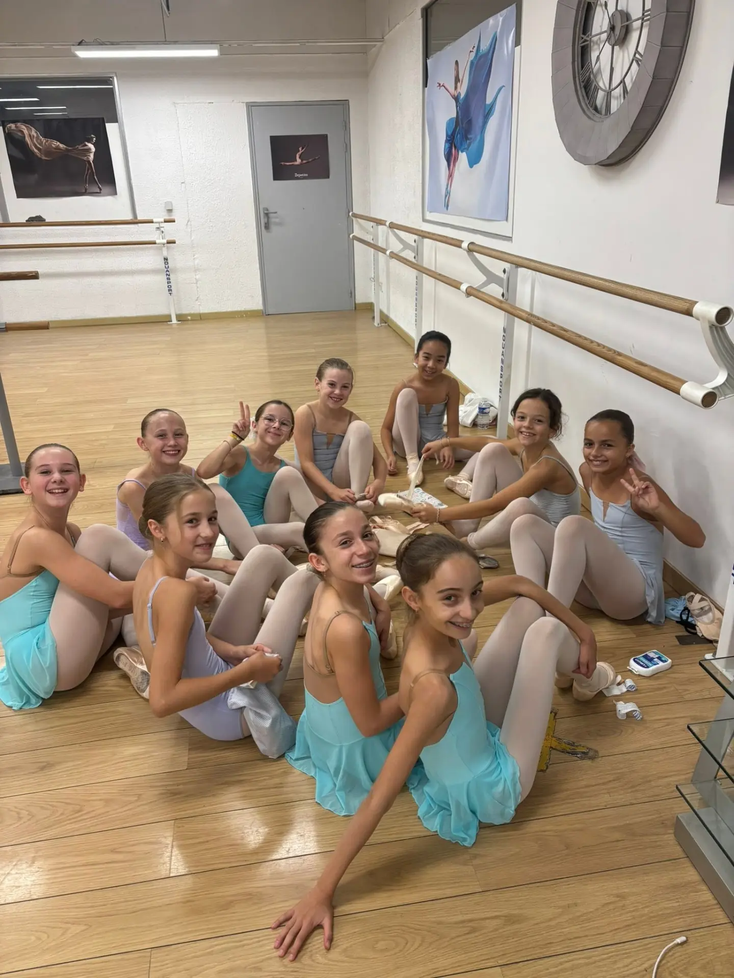 Groupe d'élèves assises au sol préparant leurs pointes en studio